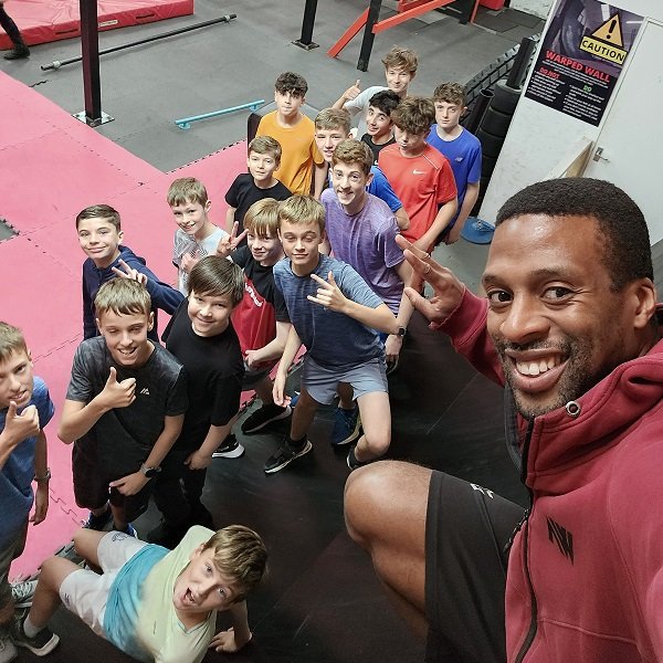 Group of kids in a ninja class or party with their coach on the warped wall